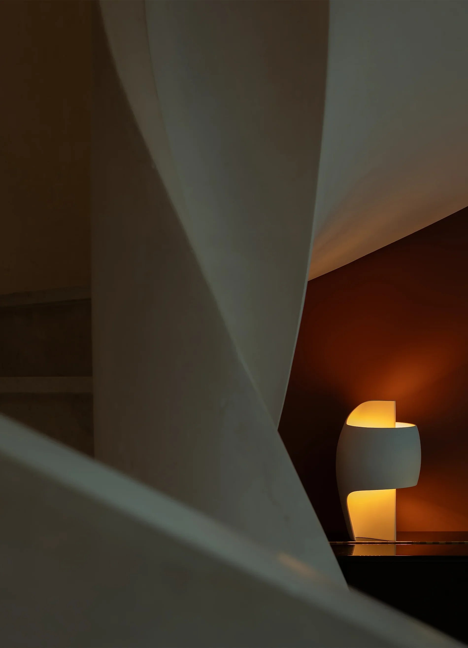 DCW Editions LampeB Grande table lamp illuminated under plaster spiral staircase with red wall