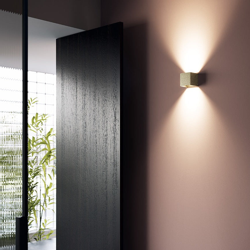 Modern wall light fixture on a textured wall with a blurred room in the background