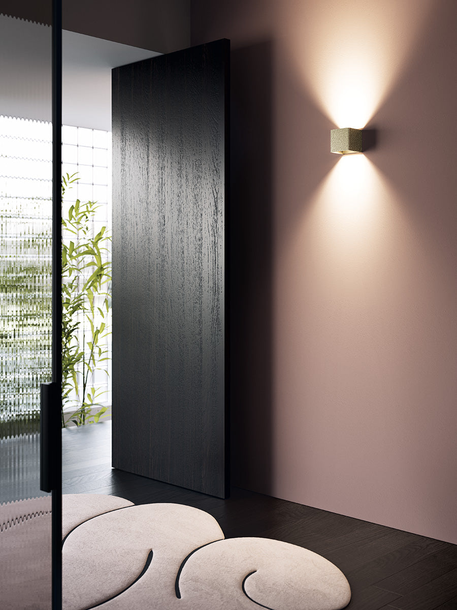 Modern interior design with a black door, wall light, and decorative stones.