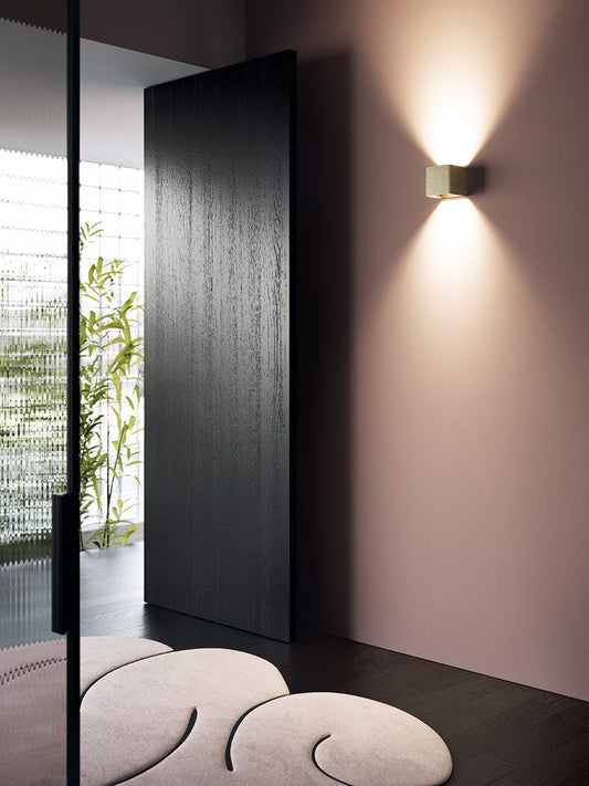 Modern interior design with a black door, wall light, and decorative stones.