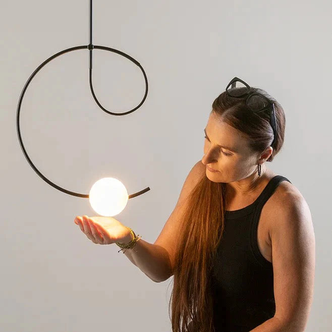 Estiluz Loop Pendant with woman cupping the illuminated glass sphere