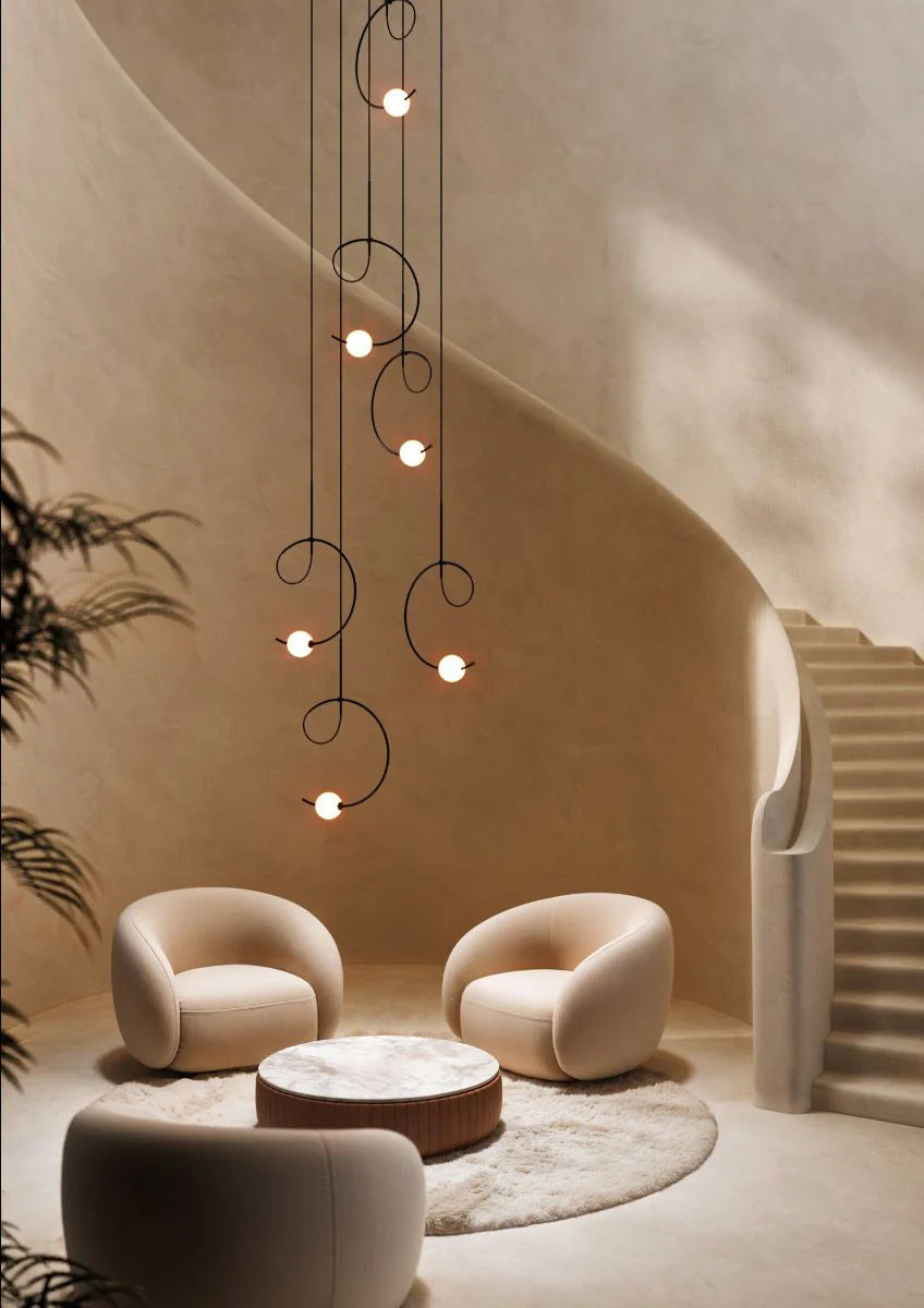 Estiluz Loop Pendant Chandelier in black finish with white glass spheres in modern spiral staircase with soft chairs below