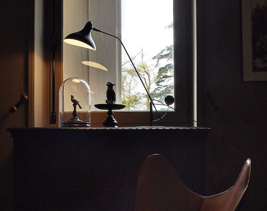 DCW Editions Mantis table lamp on sideboard with bird objects in front of a window
