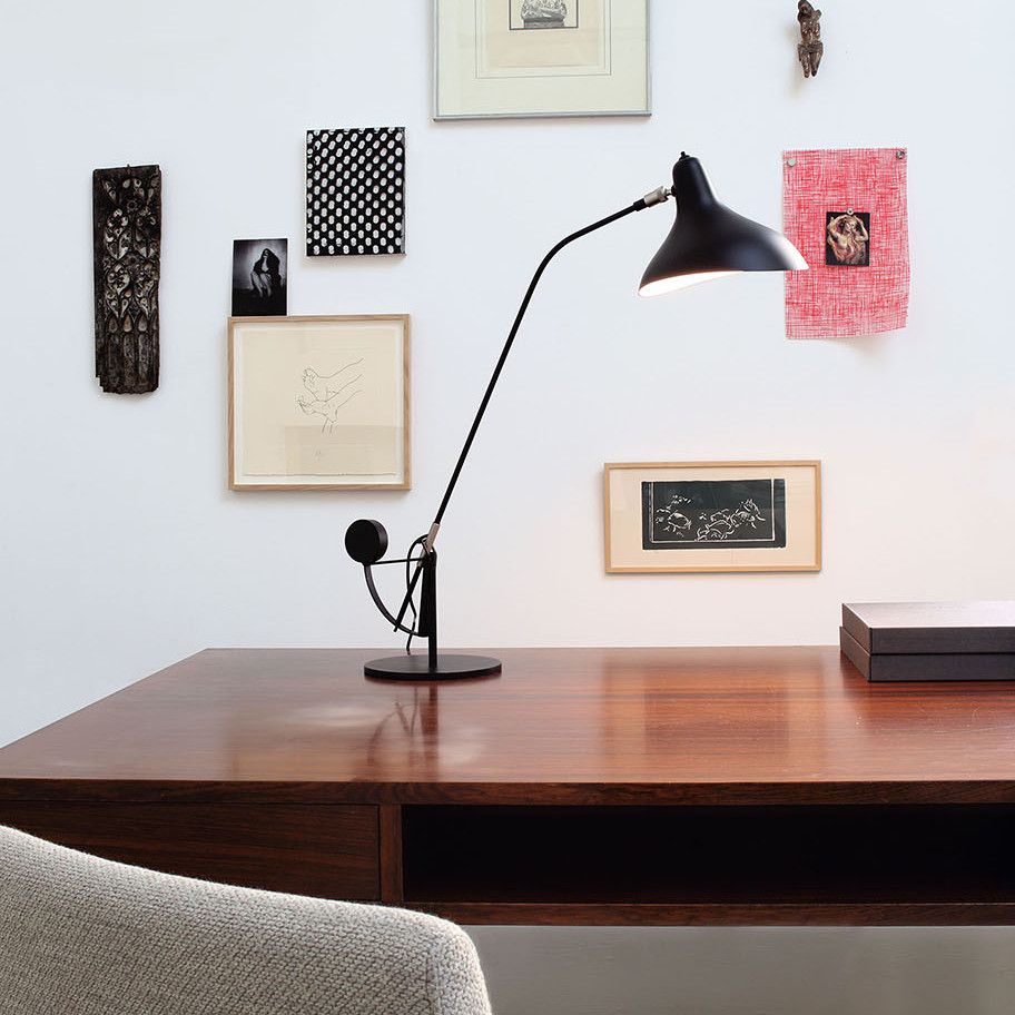DCW Editions Mantis table lamp on wooden desk with art work on the wall