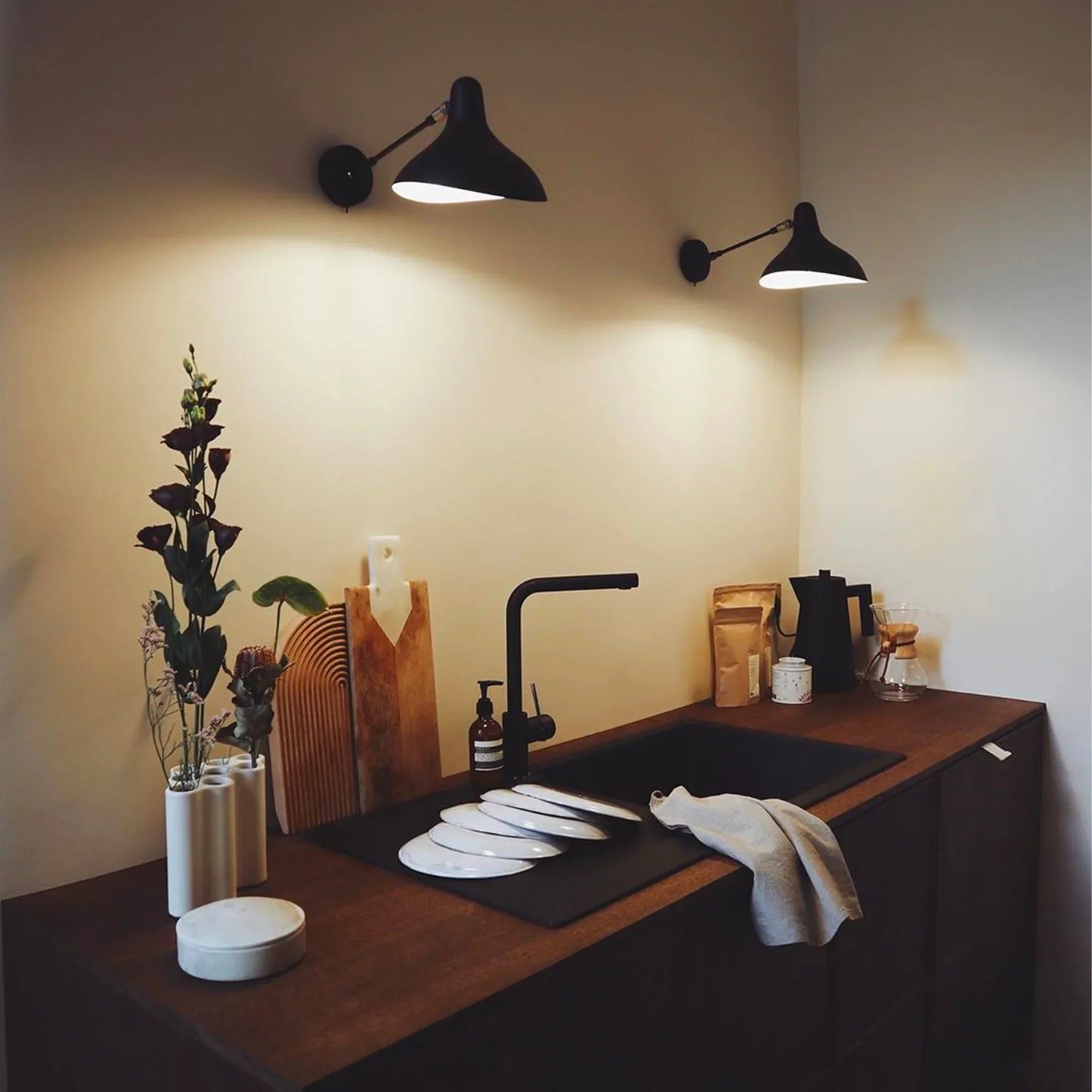 DCW Editions Mantis wall light standard BS5 with thumbswitch over small, modern kitchen  with a black sink and white plates