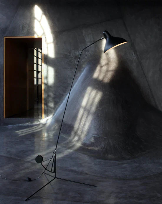 DCW Editions Mantis floor lamp BS1 in a grey room with a large bulge in the floor going up the wall and doorway