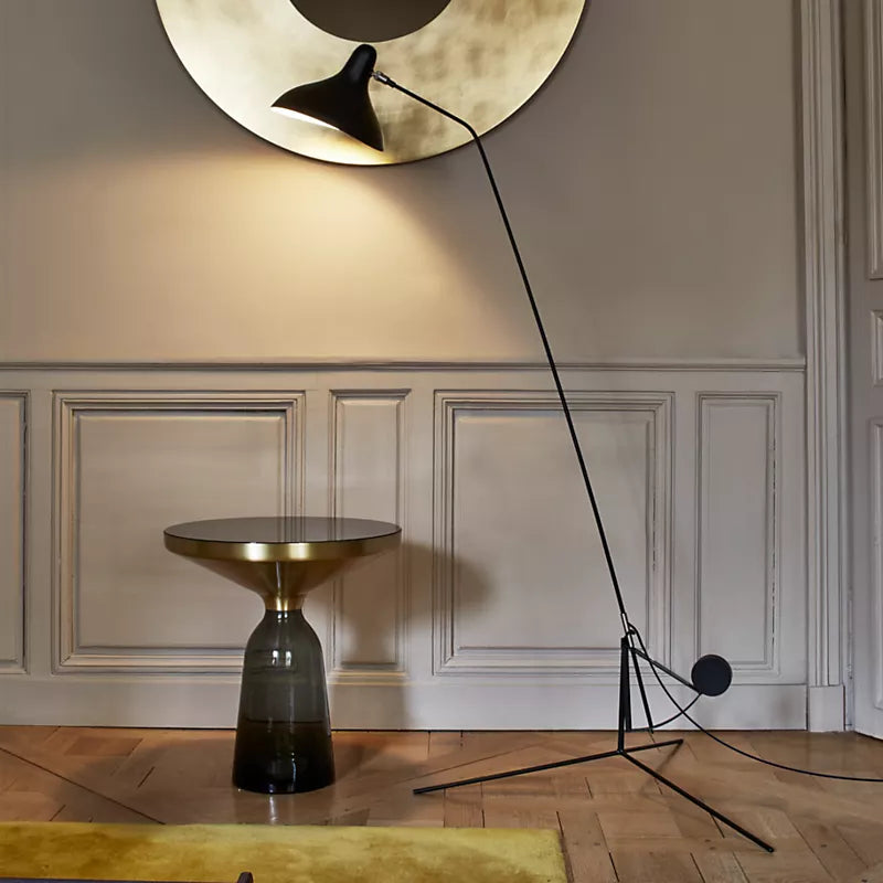 DCW Editions Mantis floor lamp BS1 on wooden floor with stylish side table, round wall sculpture and a dado wall