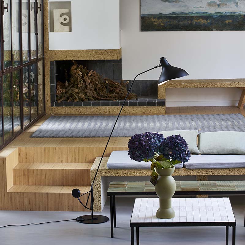 DCW Editions Mantis floor lamp BS1 in sunken lounge with a built-in bench and coffee table with flowers