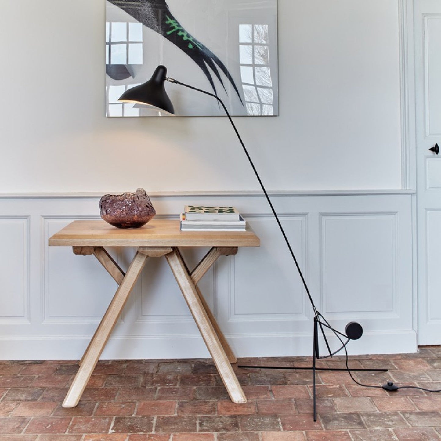 DCW Editions Mantis floor lamp BS1 over small square table with large crystal on brick floor