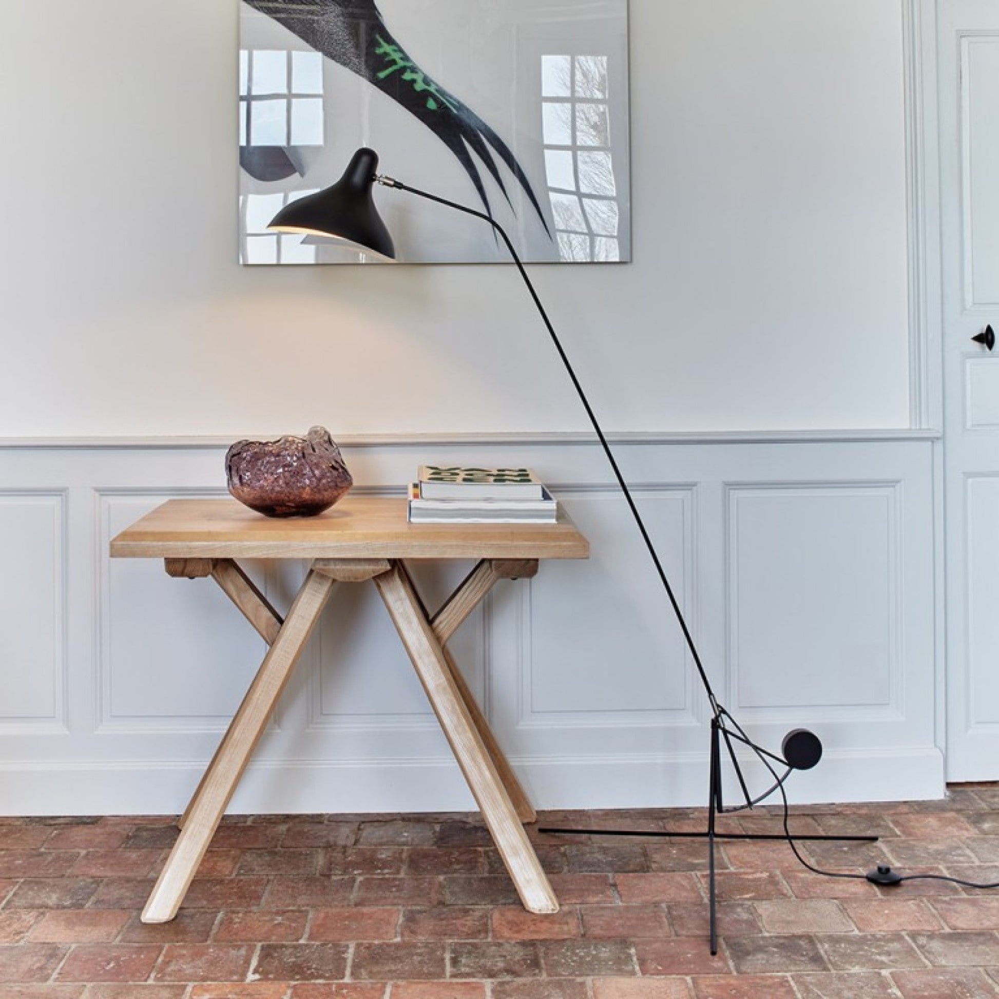 DCW Editions Mantis floor lamp BS1 over small square table with large crystal on brick floor