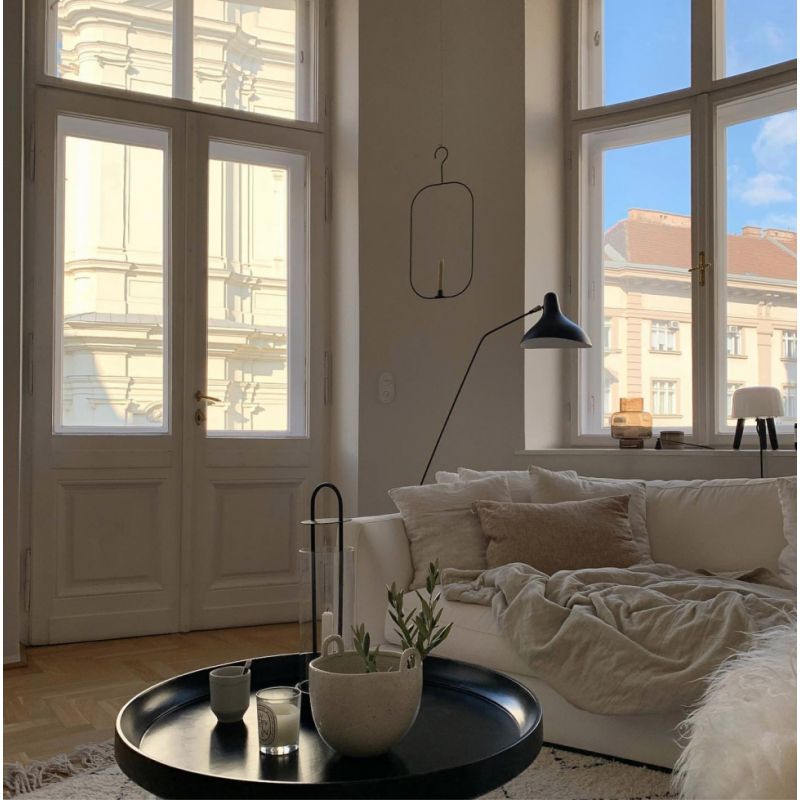 DCW Editions Mantis floor lamp BS1 over a white sofa with cushions and a blanket in a lounge with large windows