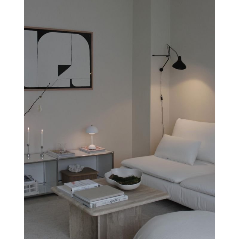 DCW Editions Mantis plug-in wall light BS2 above white sofa with table lamp and candles nearby