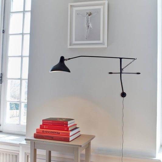 DCW Editions Mantis plug-in wall light BS2 above small table with red books