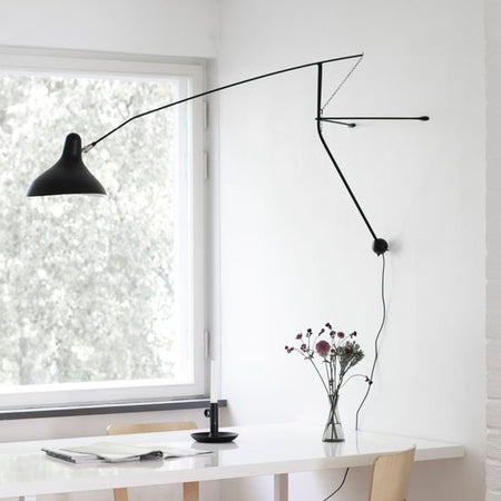 DCW Editions Mantis plug-in wall light BS2 above white table with flowers and a candle in front of a large window