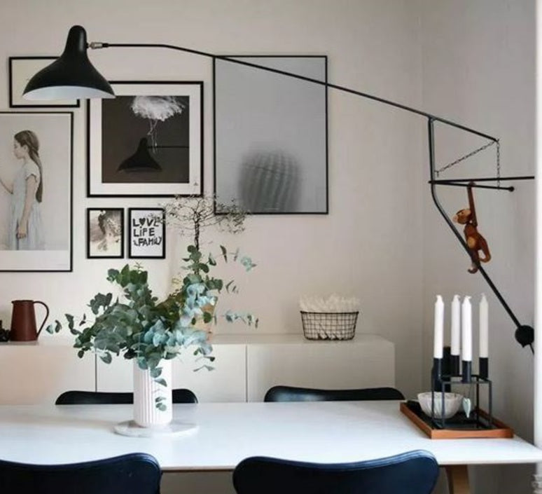DCW Editions Mantis plug-in wall light BS2 above small white table with wooden monkey hanging from the light