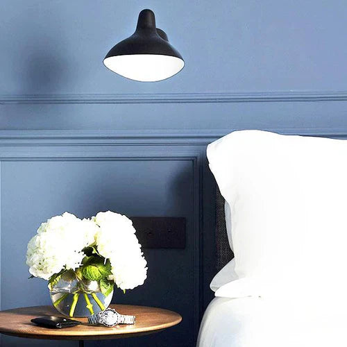 DCW Editions Mantis wall light mini BS5 on blue wall next to bed with flowers on a nightstand
