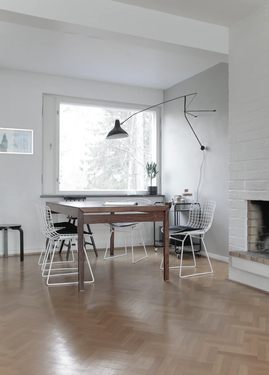 DCW Editions Mantis extending wall light over square dining table with white metal chairs