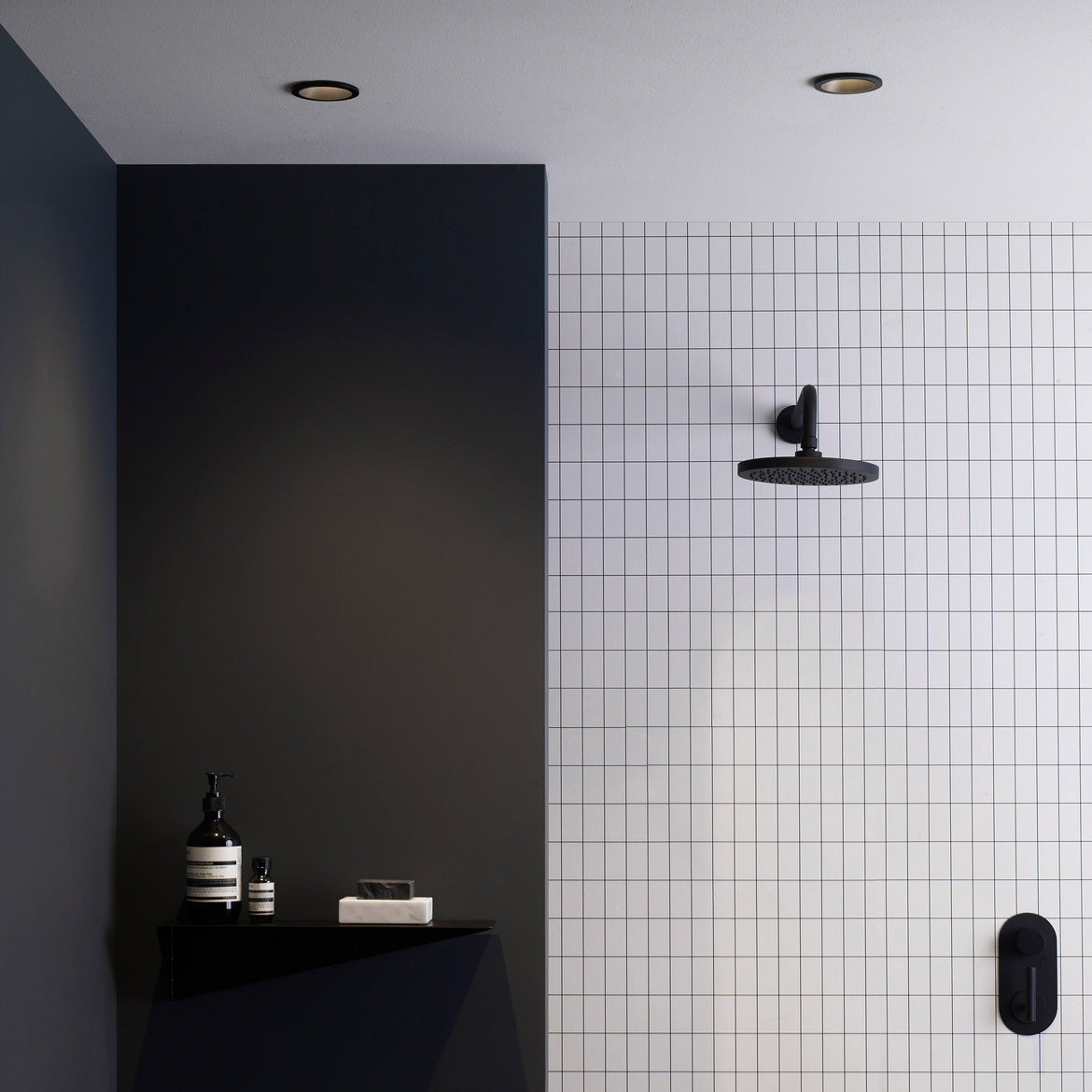 Modern bathroom with black wall, white tiled wall, and shower head.