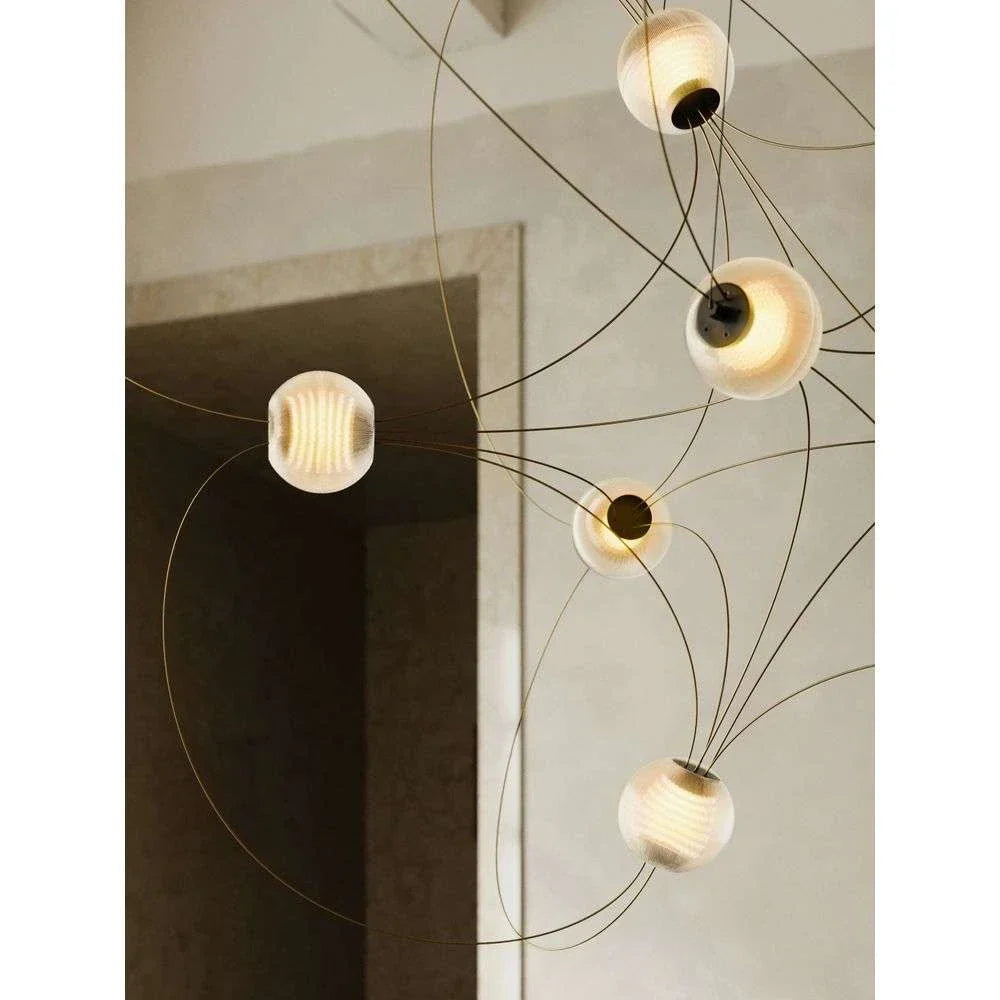 DCW Editions Munari pendant with illuminated acrylic spheres and gold curved rods close up by doorway