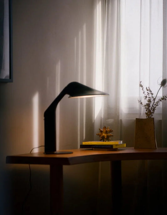 DCW Editions Niwaki black desk light on wooden table with books and evening shadows