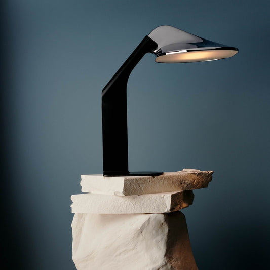 DCW Editions Niwaki black and chrome desk light on white, stacked stones with blue background
