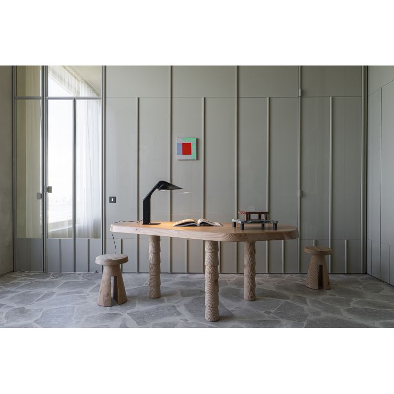 DCW Editions Niwaki black desk light on wooden table with book in a room with a stone floor, panelling and a mirror