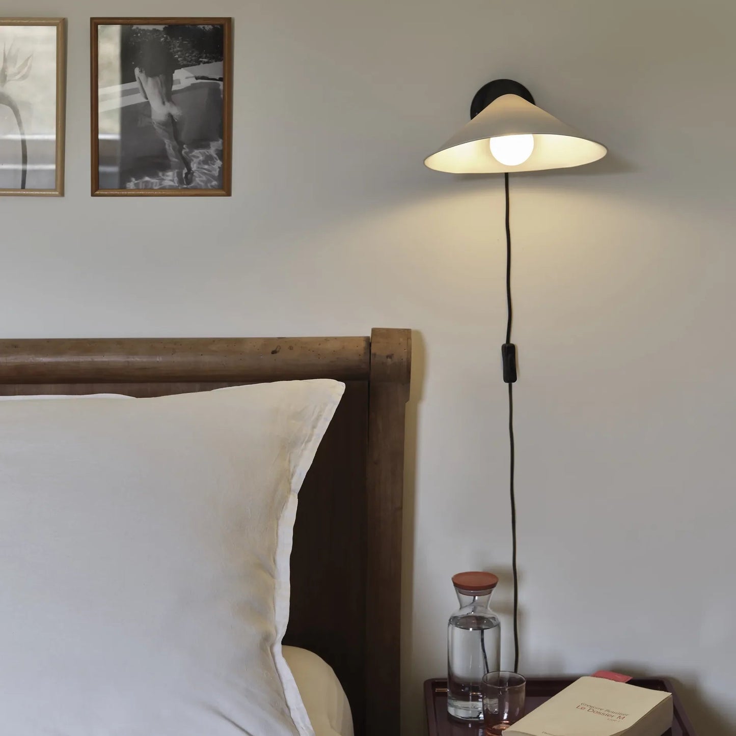 DCW Editions Plume Wall Light over with cable and switch next to a bed with a small night stand