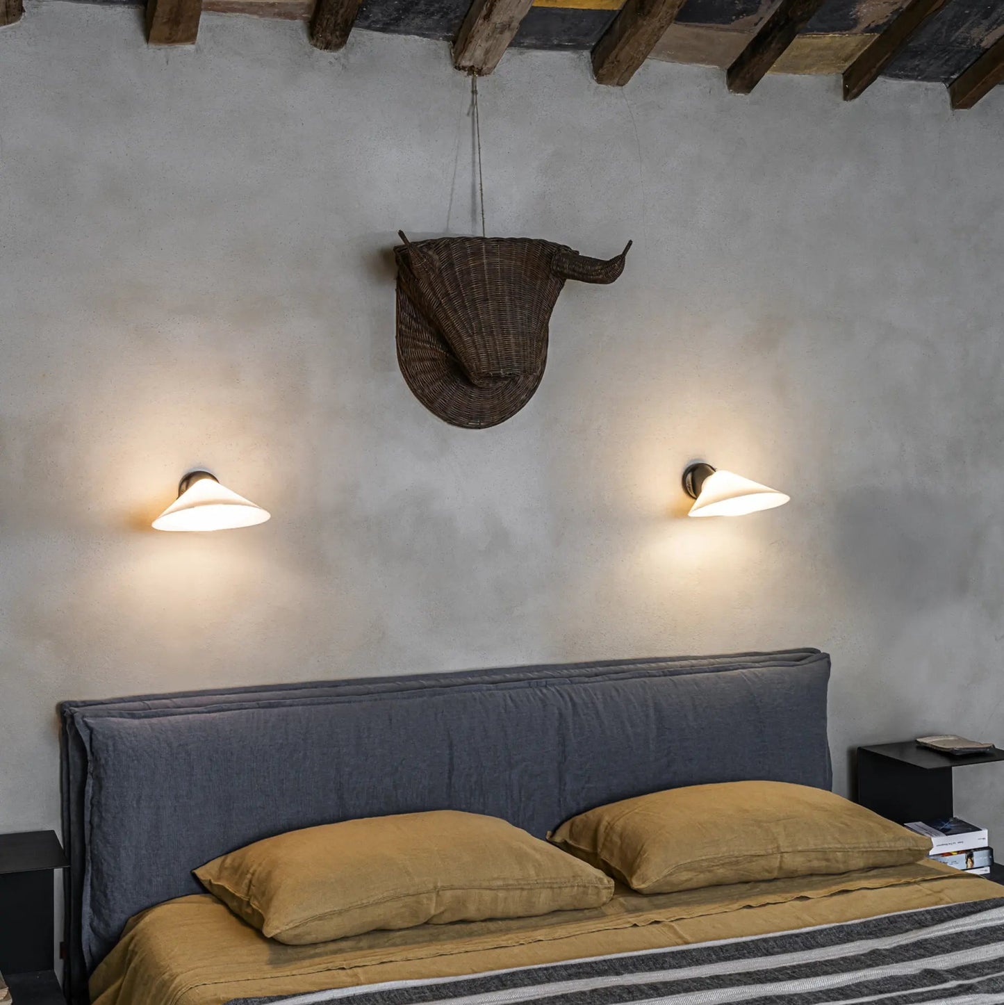 DCW Editions Plume Wall Lights over bed with striped bedding and a bull head on the wall above