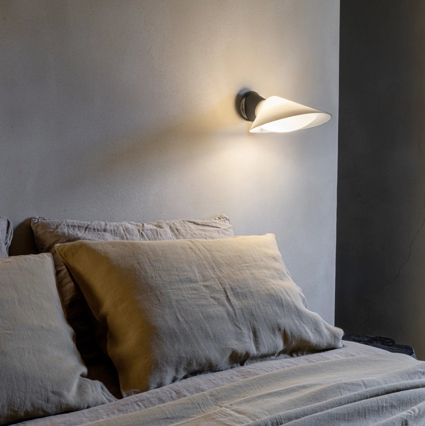 DCW Editions Plume Wall Light over bed with soft linen bedding