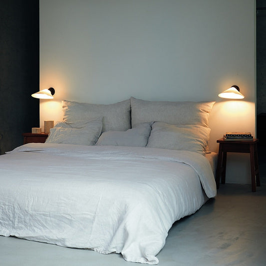 DCW Editions Plume wall light on either side of a large bed with lots of cushions