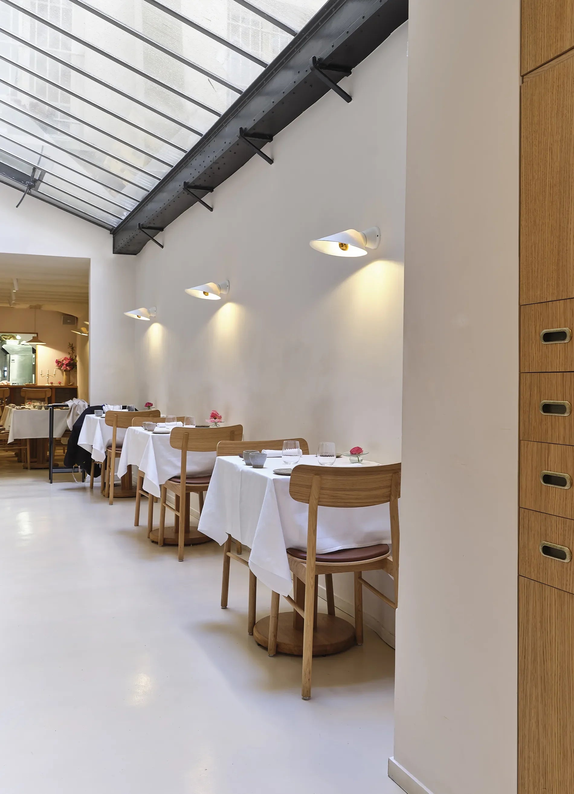 DCW Editions Plume Wall Lights over small square tables with a sky light above
