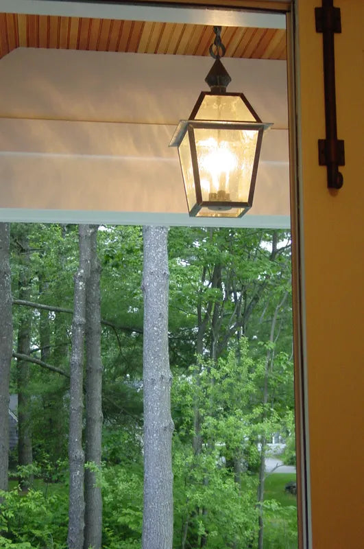 Lantern hanging in porch by front door with the woods outside
