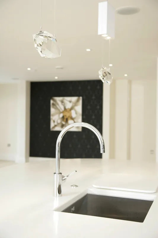 Modern crystal pendant hanging over a black sink with chrome taps
