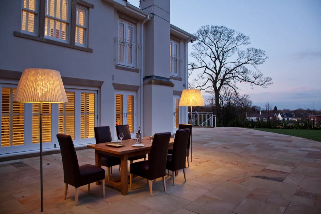 Outdoor floor lamps by outside dining table in back garden of a house