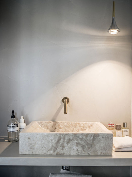 Lodes Rain pendant in chrome shining a beam downwards into a corner of a modern, minimal, stone sink
