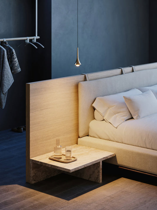 Lodes Rain pendant in champagne hung by a bed with with a low wooden bedside table