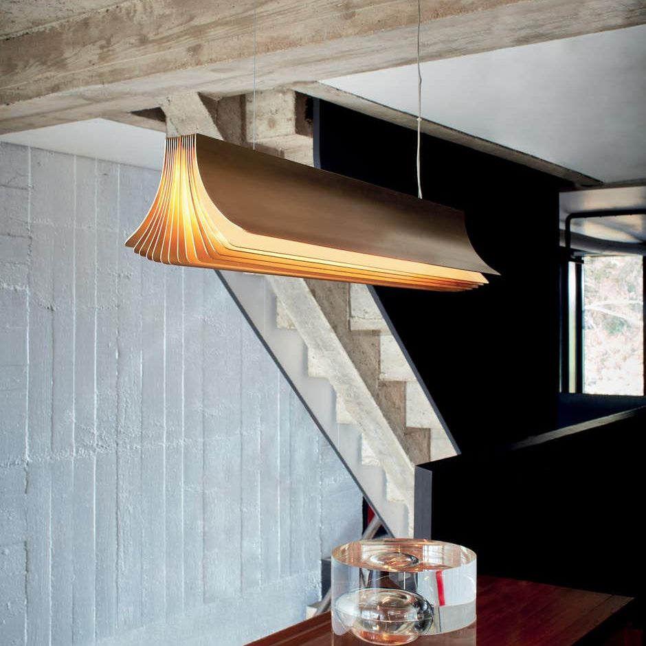 DCW Editions Respiro gold linear pendant over narrow table with glass objects