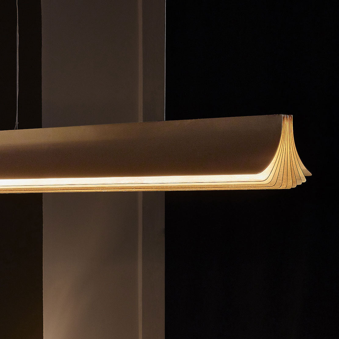 DCW Editions Respiro illuminated gold linear pendant with dark background