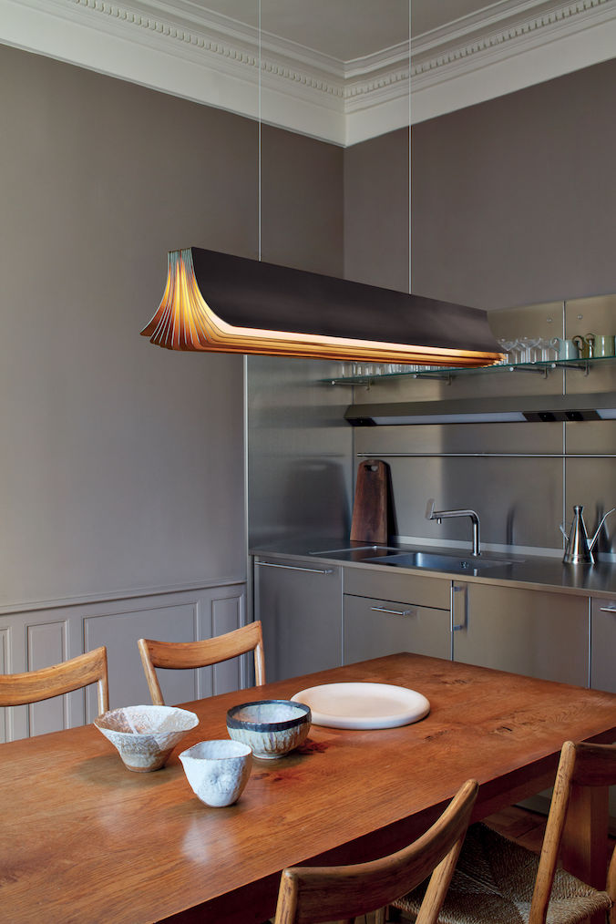 DCW Editions Respiro black and gold 1200mm linear pendant over wooden table with bowls and aluminium kitchen in the background