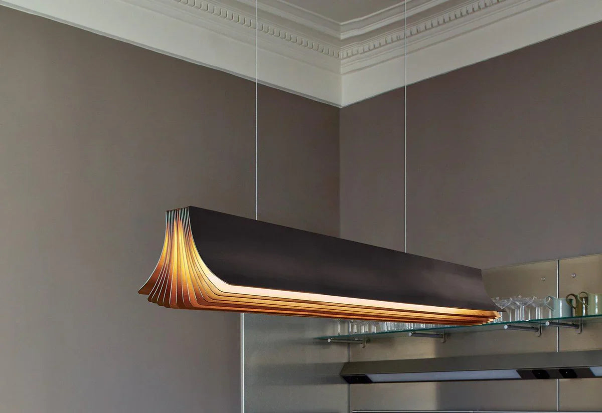 DCW Editions Respiro black and gold linear pendant illuminated in room with glass and brown walls