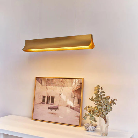 DCW Editions Respiro gold linear pendant illuminated over art work on white console table