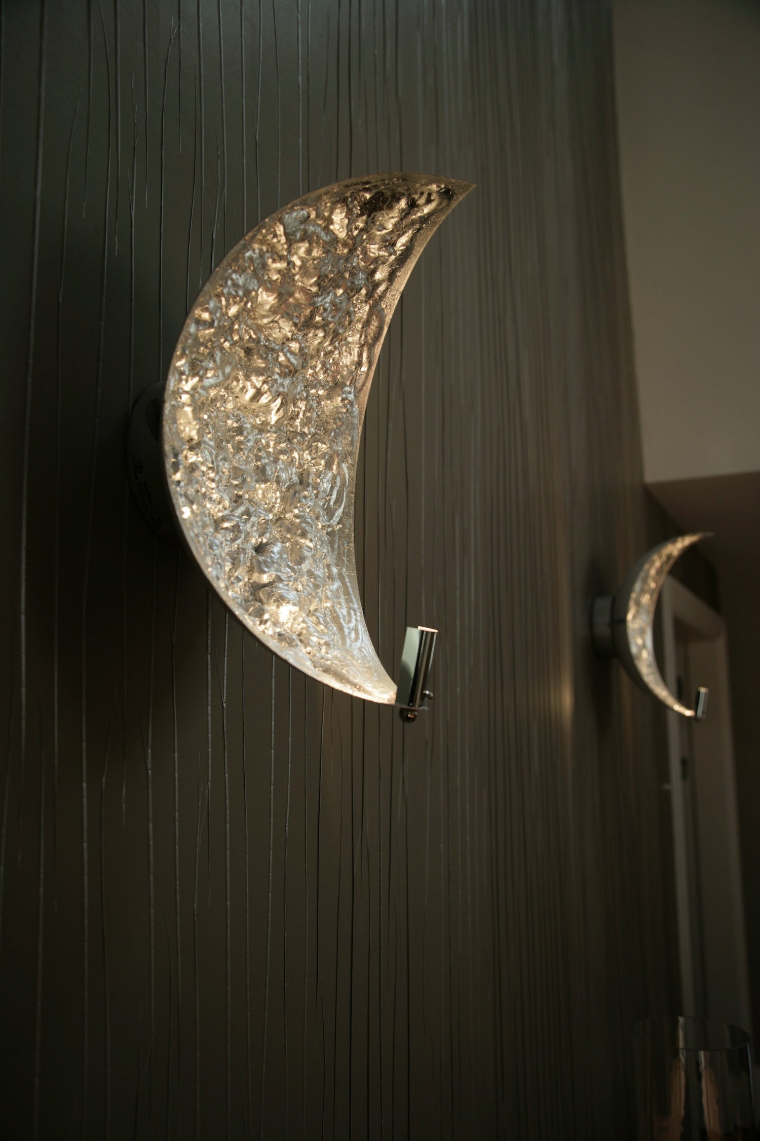 Silver-leaf wall light on dark wall