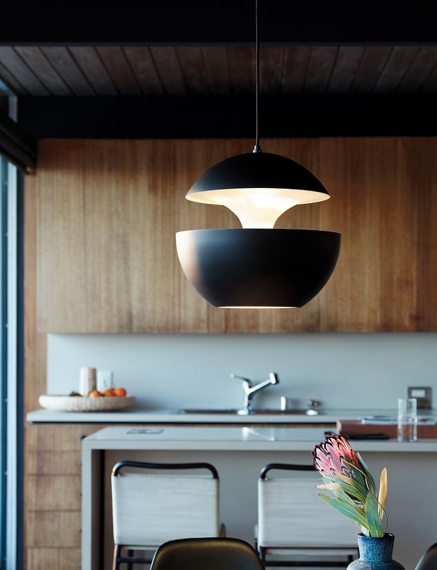 Modern kitchen with black pendant lights, wooden cabinets, and a white countertop.