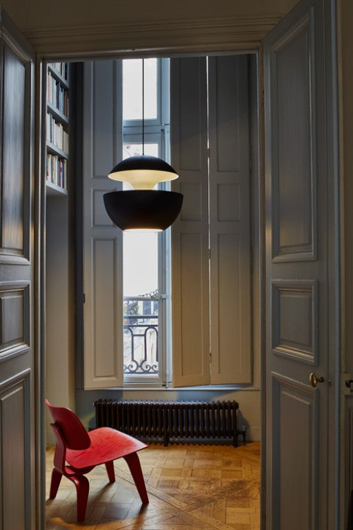 Modern interior with a red chair, hanging lights, and a large window.