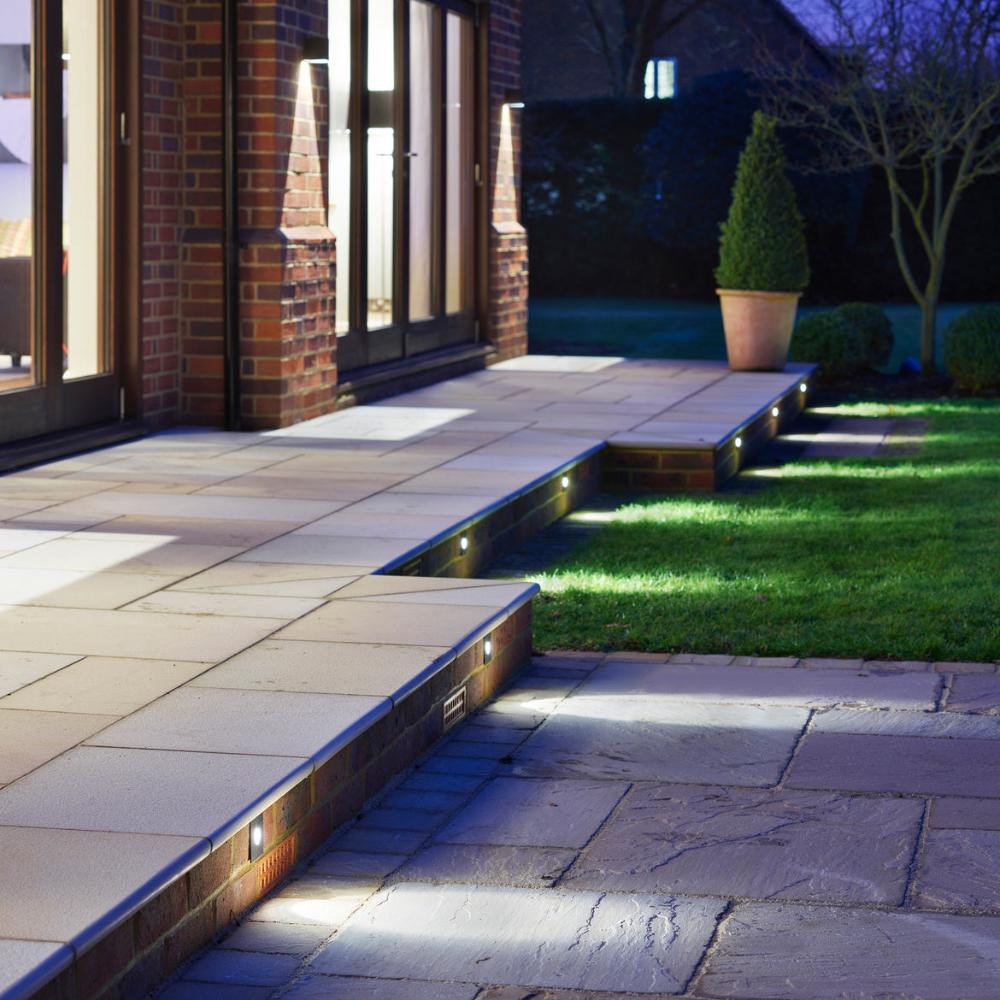 Astro Tango step light in brushed steel on outdoor patio with stone paving