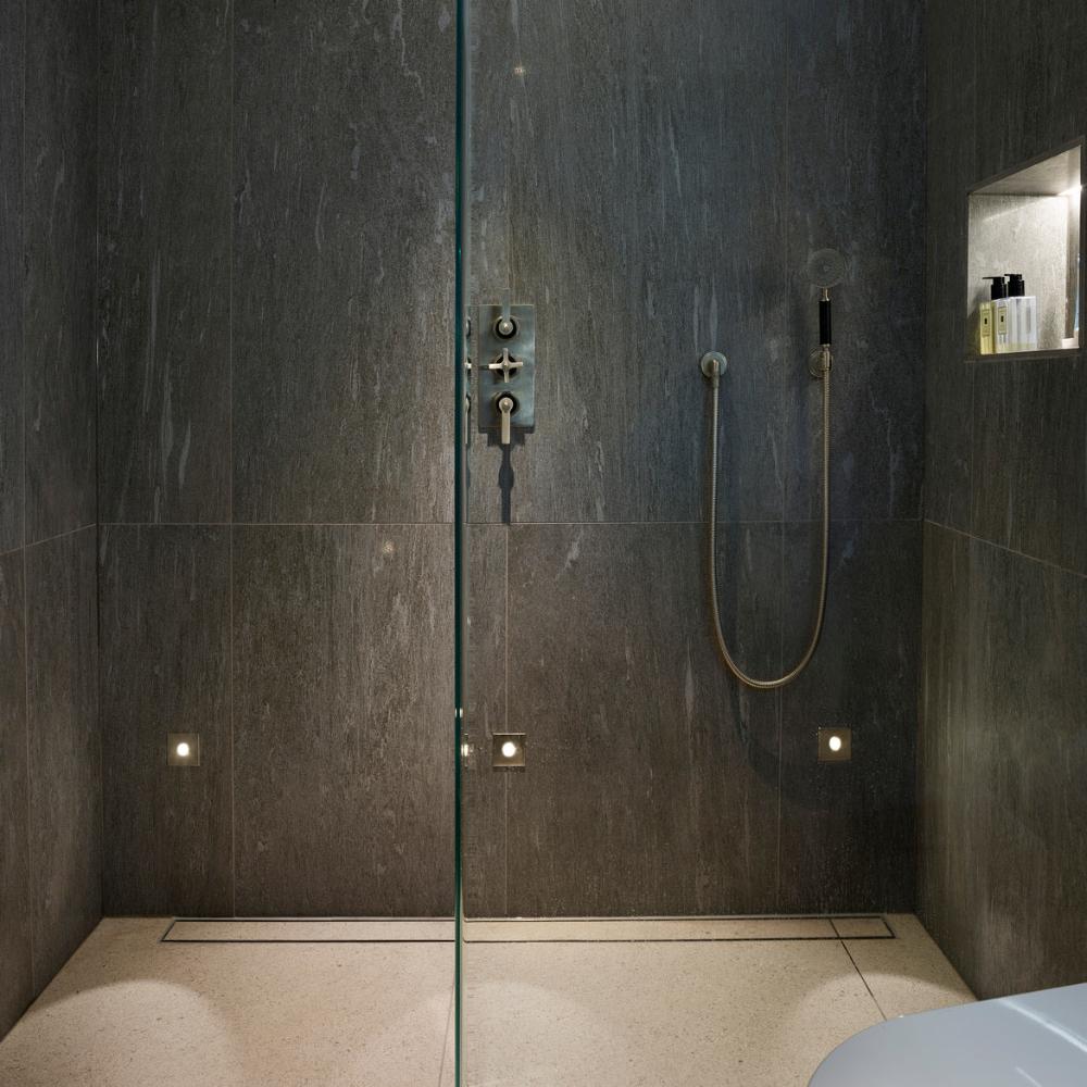 Astro Tango step light in brushed steel in dark, moody modern shower with illuminated shower niche