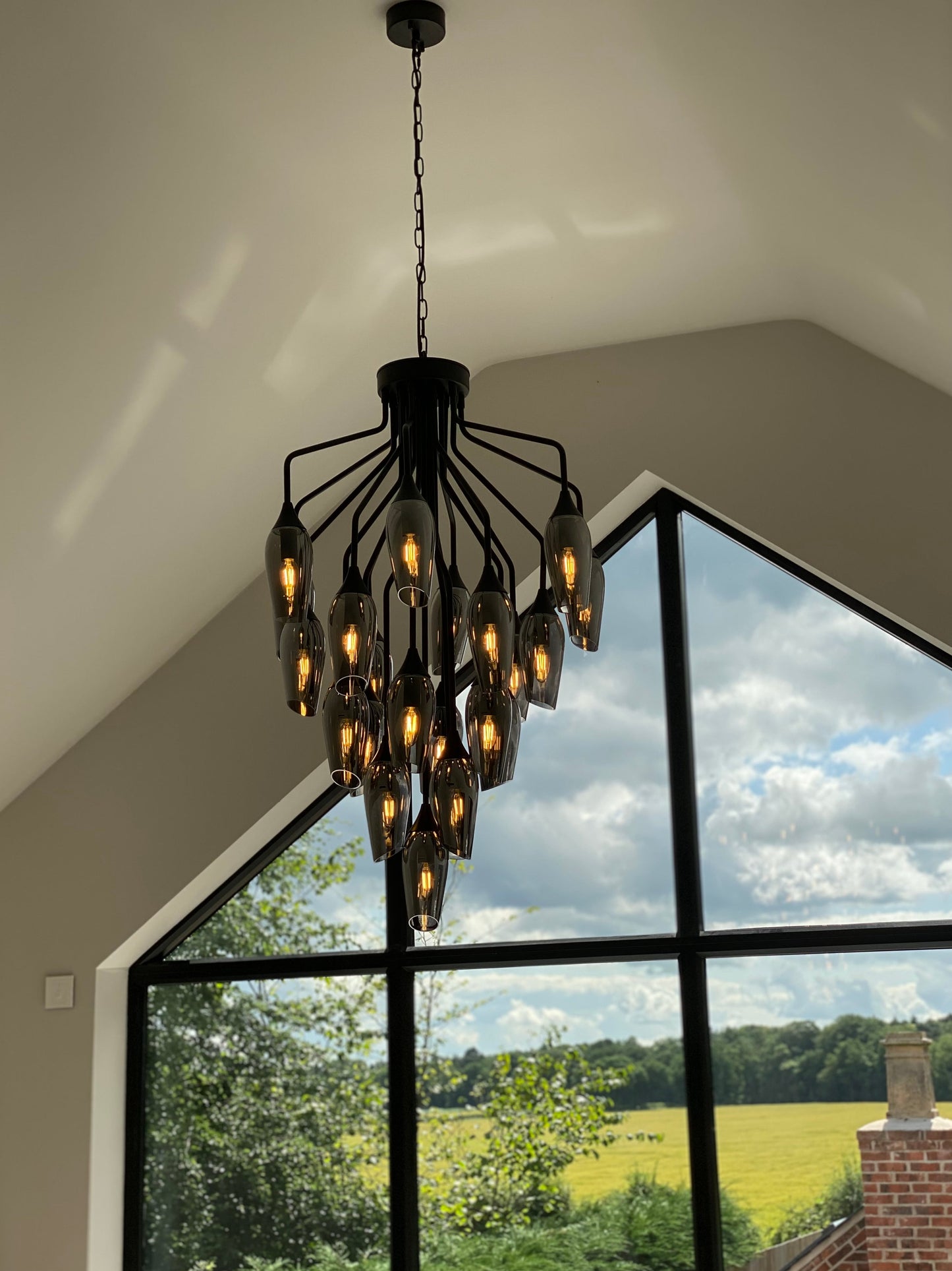 Softly lit chandelier in bedroom with vaulted ceilings and countryside views