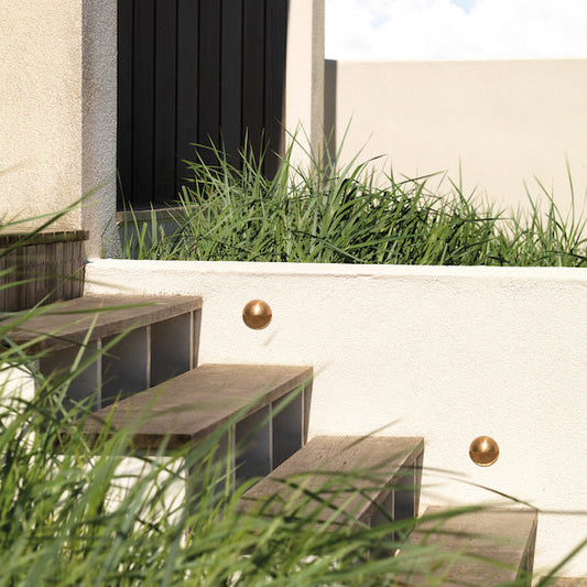 Astro tivola step light in brass on wooden outdoor steps with tall grass