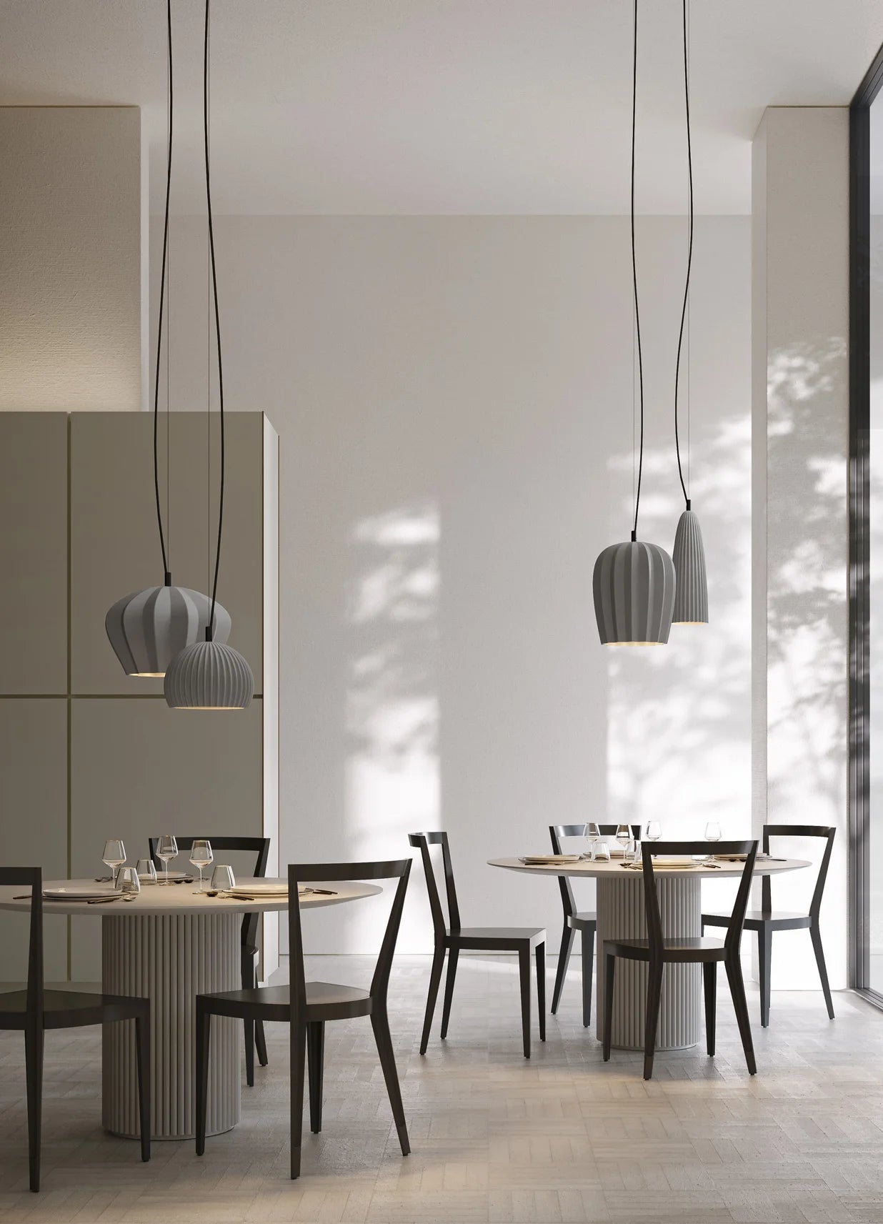 Modern dining area with grey ceramic Sahara pendant lights by Karman Italia and a neutral color palette.